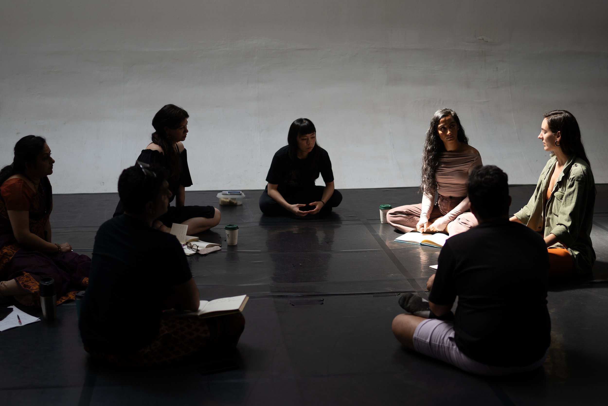 A group of dancers sit on the floor talking